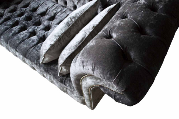 Een luxueuze, klassieke bank in Chesterfield-stijl in een diepe zilveren kleur.