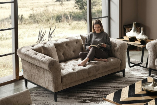 Gezellige beige Chesterfield driezitsbank voor in de woonkamer.