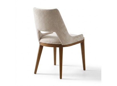 Een laconieke, moderne stoel met hoge poten van hout en bekleding in een prettige, lichte crèmekleur voor de eetkamer.