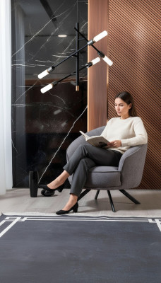 Moderne grijze fauteuil met roestvrijstalen poten, stoffen bekleding van polyester, en geschikt voor één persoon.