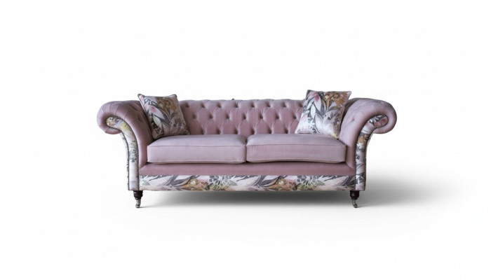 Een levendige driezitsbank van Chesterfield met een delicaat roze bloemenpatroon.