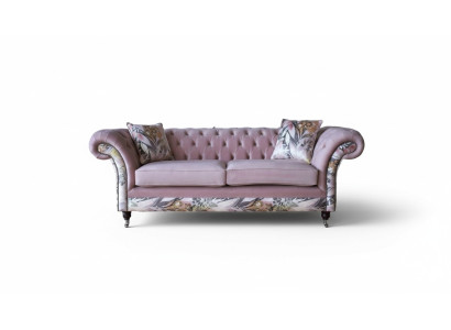 Een levendige driezitsbank van Chesterfield met een delicaat roze bloemenpatroon.